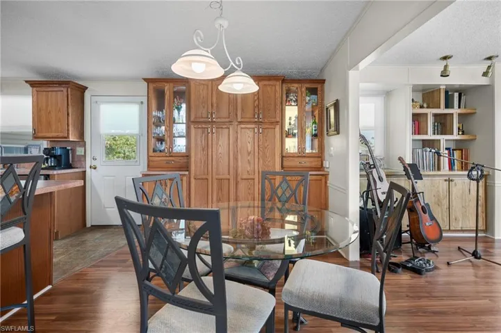Dining space with a textured ceiling, dark wood-type flooring, and crown molding