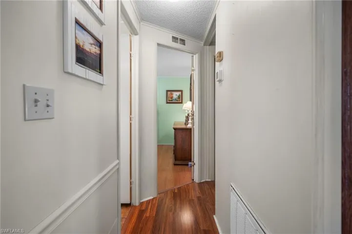 Hallway with dark wood-type flooring and a textured ceiling
