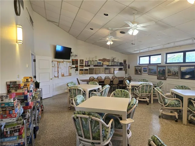 Dining space featuring a ceiling fan, a drop ceiling, and high vaulted ceiling