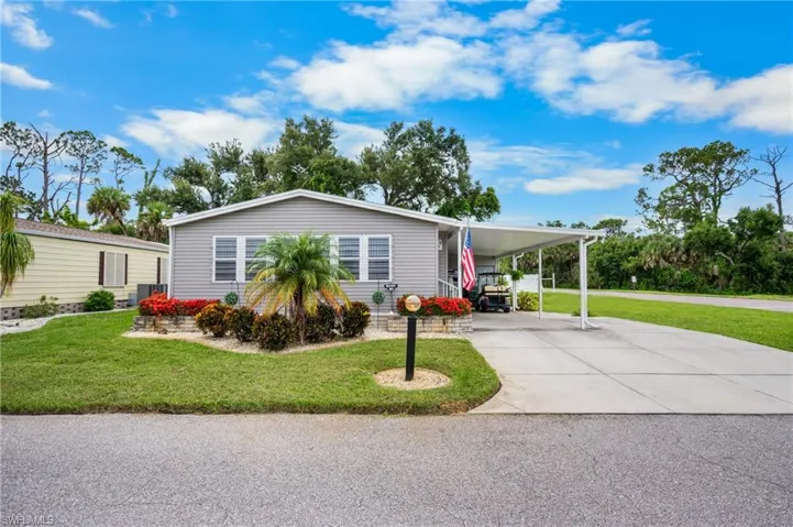 Manufactured / mobile home with a front lawn, concrete driveway, and an attached carport