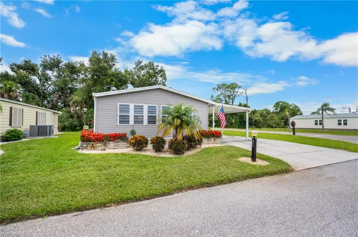 View of front of home with a front lawn, concrete driveway, and a carport