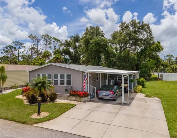 Manufactured / mobile home featuring a front yard, concrete driveway, and a carport