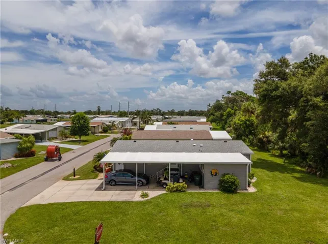 Back of property featuring a lawn, a carport, and concrete driveway