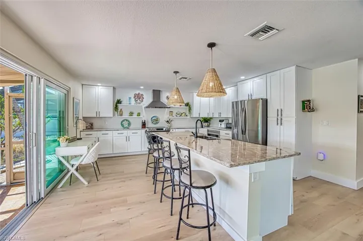 Kitchen featuring white cabinetry, stainless steel appliances, open shelves, a breakfast bar area, and a textured ceiling