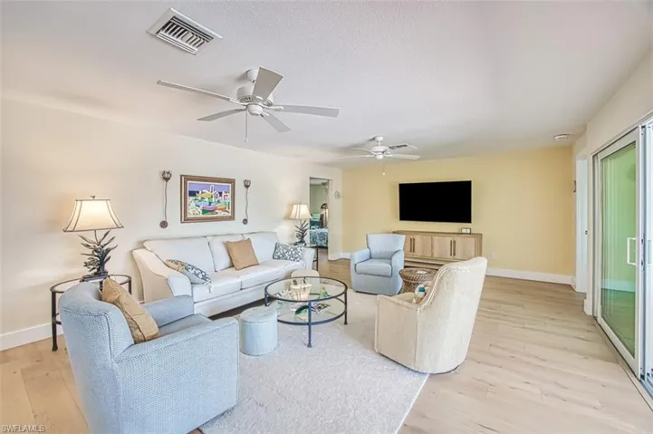 Living area featuring light wood-style flooring, ceiling fan, and a textured ceiling
