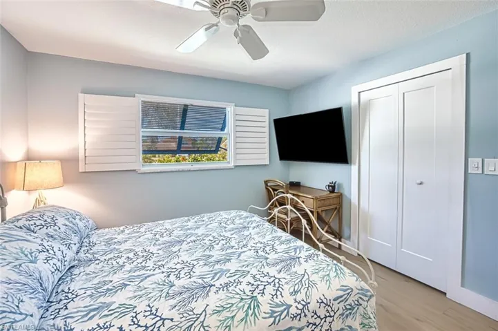 Bedroom with light wood finished floors, a ceiling fan, and a closet