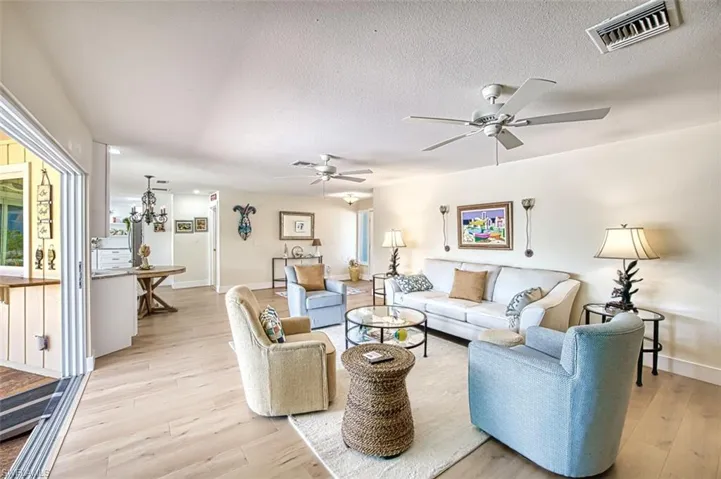 Living room featuring a ceiling fan, light wood finished floors, and a textured ceiling
