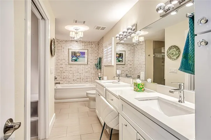 Bathroom featuring double vanity, a stall shower, a garden tub, and light tile patterned floors