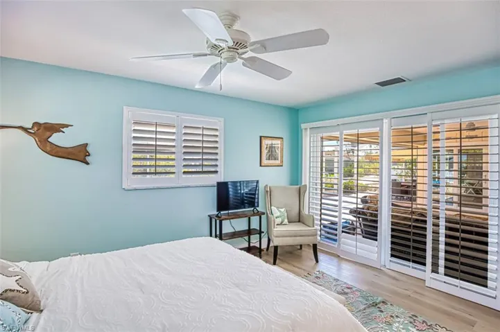 Bedroom with access to outside, multiple windows, wood finished floors, and a ceiling fan