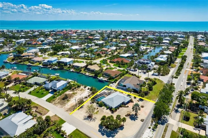 Aerial view of residential area with property parcel outlined and a large body of water
