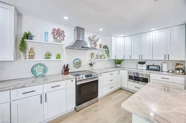 Kitchen featuring white cabinetry, open shelves, light stone counters, stainless steel appliances, and recessed lighting
