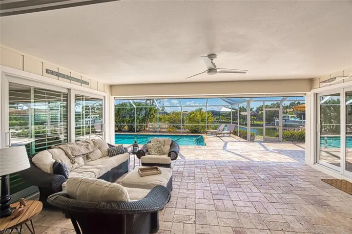 View of patio with an outdoor hangout area, a sunroom, a ceiling fan, glass enclosure, and an outdoor pool