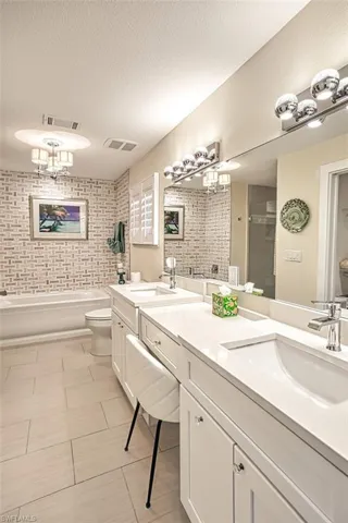 Full bath with double vanity, a textured ceiling, a stall shower, and a garden tub