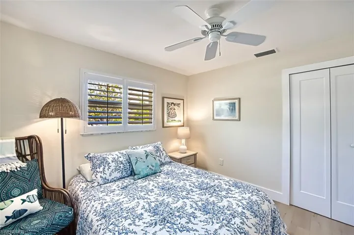 Bedroom with a ceiling fan, light wood-style floors, and a closet