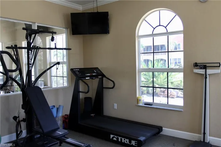 Exercise room featuring ornamental molding and baseboards