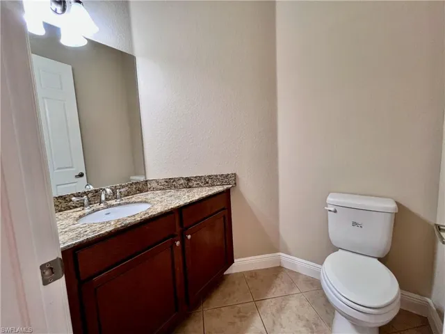 Half bath with a textured wall, vanity, and light tile patterned floors