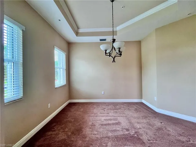 Formal Dining Room featuring carpet floors, a tray ceiling, ornamental molding, and a chandelier
