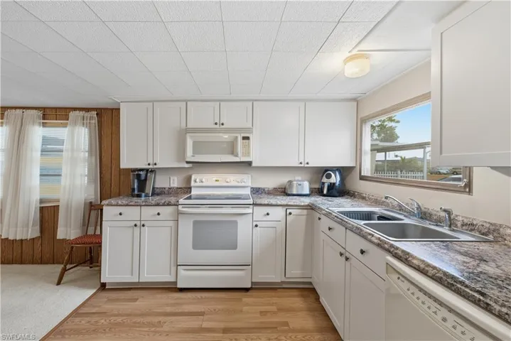 Kitchen with white appliances, white cabinetry, and light wood-style flooring