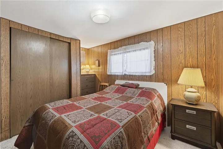 Carpeted bedroom featuring a closet and wood walls