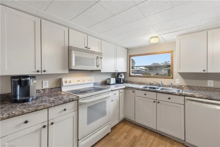 Kitchen featuring white appliances, white cabinets, and light wood-type flooring