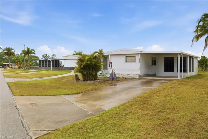 View of front of house featuring a front lawn, an attached carport, and concrete driveway