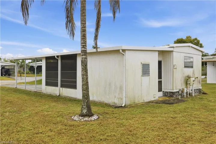 View of property exterior with a lawn, a sunroom, and a carport