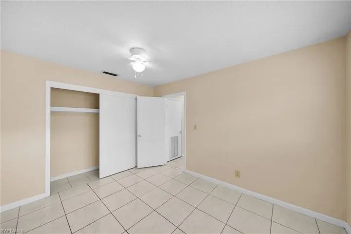 Unfurnished bedroom with a closet, light tile patterned floors, a ceiling fan, and a textured ceiling