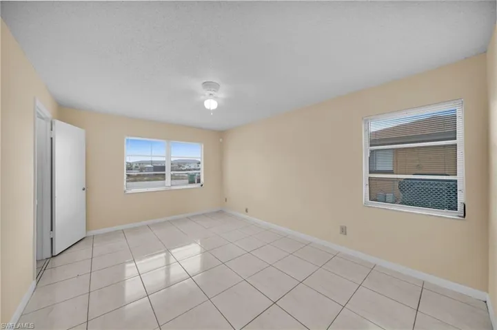 Unfurnished room featuring a textured ceiling, light tile patterned flooring, and ceiling fan