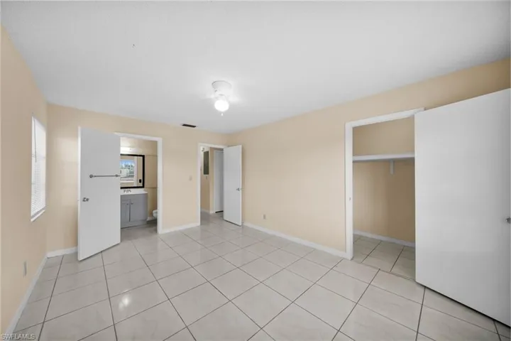 Unfurnished bedroom featuring light tile patterned floors, a spacious closet, and connected bathroom