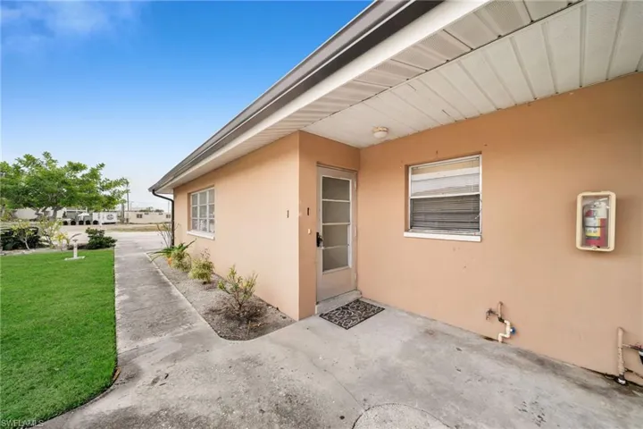 Entrance to property with a yard and stucco siding
