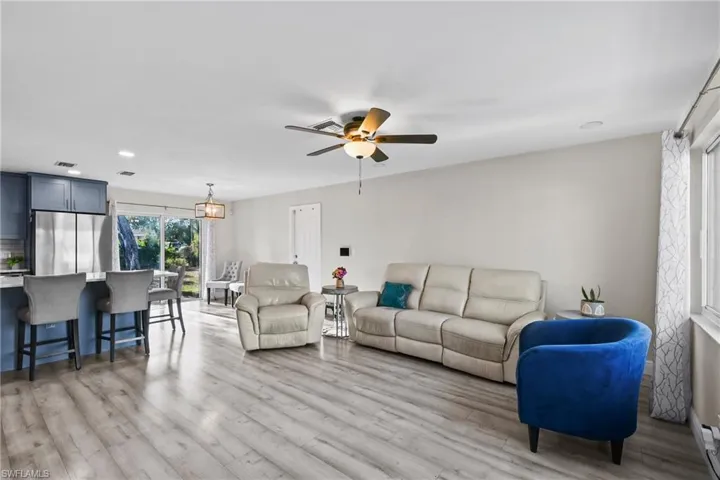 Living area with light wood-type flooring, ceiling fan, recessed lighting, and a baseboard heating unit