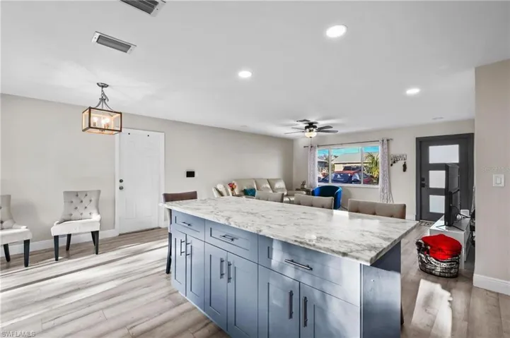 Kitchen with recessed lighting, light stone countertops, decorative light fixtures, open floor plan, and a kitchen island