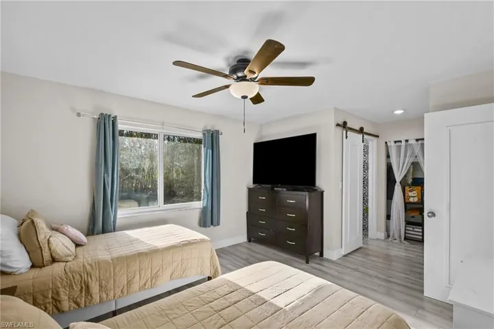 Bedroom featuring a barn door, ceiling fan, light wood-style flooring, and recessed lighting