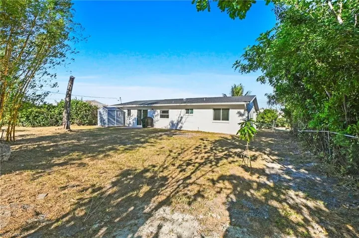 View of front of house featuring a storage shed, a fenced backyard, and stucco siding