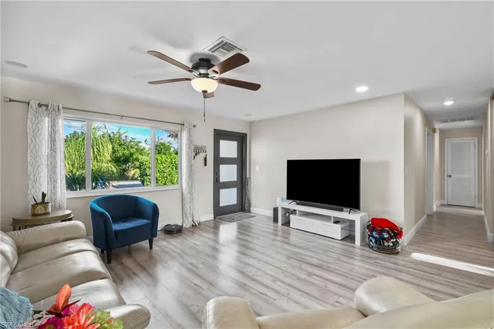 Living room featuring light wood-style flooring, ceiling fan, and recessed lighting