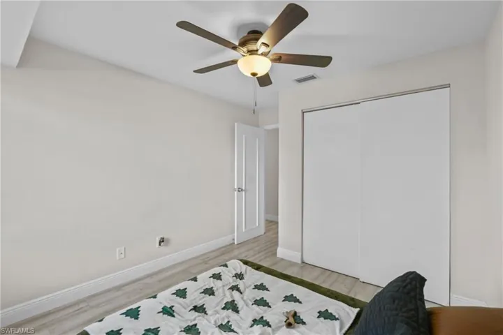 Bedroom with light wood-style floors, ceiling fan, and a closet