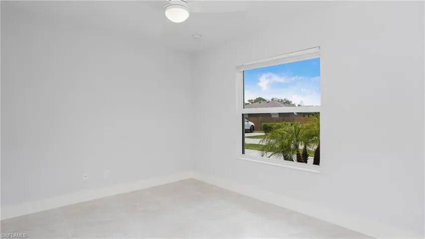 Bright interior space featuring a window with a tropical landscape beyond, light-toned wall paint, a ceiling fan with integrated lighting, and recessed ceiling lighting