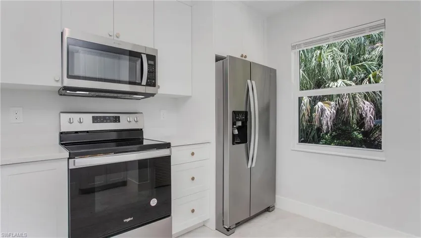 Kitchen featuring white cabinetry, light-toned countertops, stainless steel appliances including a refrigerator and range, and an over-the-range microwave