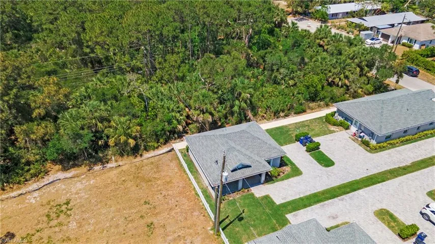 Aerial perspective showcasing the property with a gray shingle roof and light gray exterior, featuring a paved driveway and green lawn