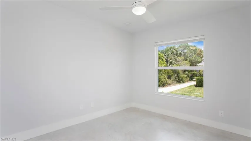 Bright room featuring a ceiling fan with integrated lighting, a large window, tiled flooring, and tall baseboards