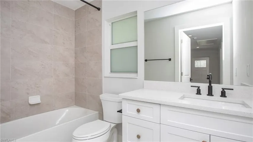 Bathroom featuring a white vanity with shaker-style cabinetry, a white countertop, and a rectangular undermount sink with a matte black faucet