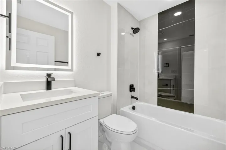 Bathroom with vanity, shower / washtub combination, and a textured wall