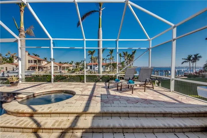 View of patio / terrace featuring a lanai and an in ground hot tub