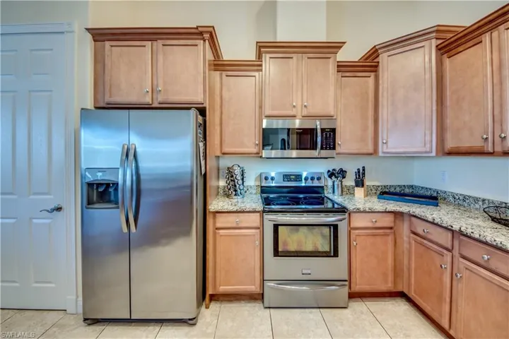 Kitchen with light stone counters, light tile patterned floors, and stainless steel appliances