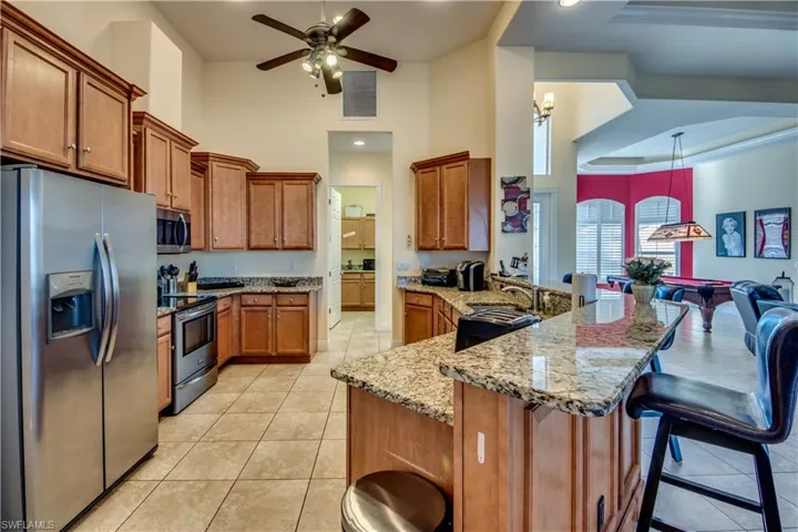 Kitchen with a kitchen bar, light tile patterned floors, stainless steel appliances, and decorative light fixtures