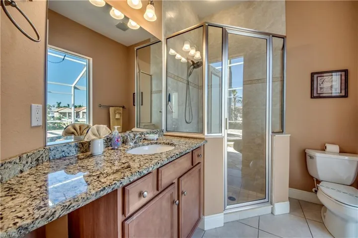 Bathroom with toilet, vanity, tile patterned floors, and an enclosed shower