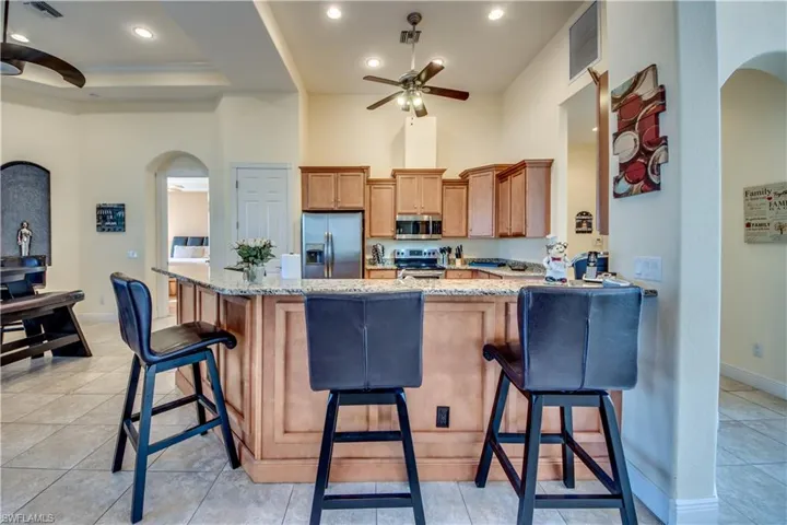 Kitchen with kitchen peninsula, a breakfast bar, stainless steel appliances, and light stone counters