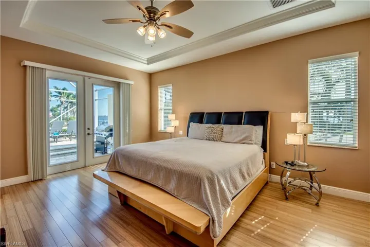Bedroom with ceiling fan, french doors, a raised ceiling, light hardwood / wood-style flooring, and access to outside