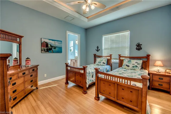 Bedroom featuring ceiling fan, ornamental molding, a tray ceiling, and light hardwood / wood-style flooring