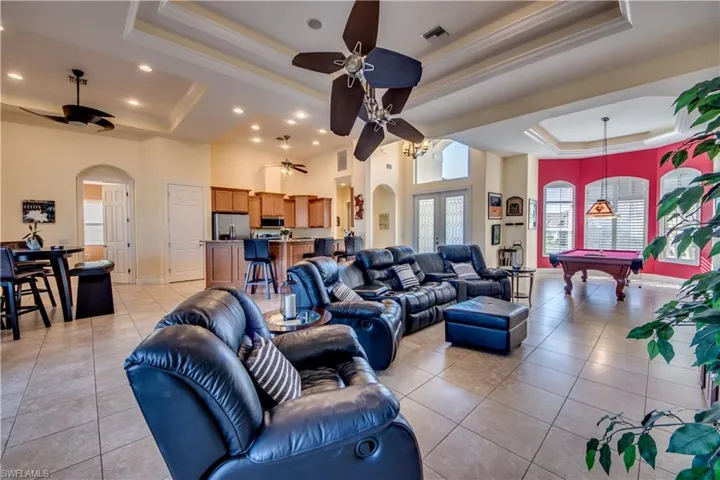 Living room with a tray ceiling, light tile patterned flooring, a high ceiling, and billiards